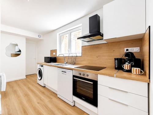 a kitchen with white cabinets and a stove top oven at 8B - Le Cosy in Saint-Rambert-dʼAlbon