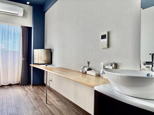 a bathroom with a large white sink and a counter at HOTEL Progress inn 名護 MATABee in Nago
