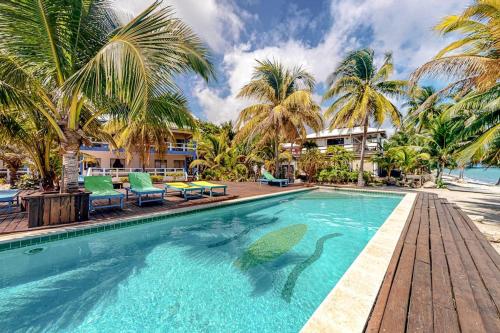 a swimming pool with palm trees and a resort at Condo #23 @ Beachside Villas in Placencia