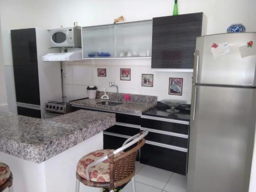 una cocina con nevera de acero inoxidable y armarios en Residencial André Reis, en Fortaleza