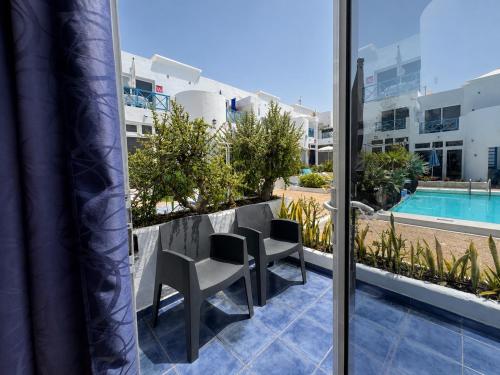 a balcony with a table and chairs and a pool at Vanessa Puerto del Carmen in Tías