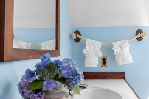 a bathroom sink with towels and a vase of flowers at Inn at the Oaks in Eastham
