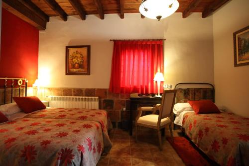 1 dormitorio con 2 camas, escritorio y cortina roja en Douris Temple, en Soria