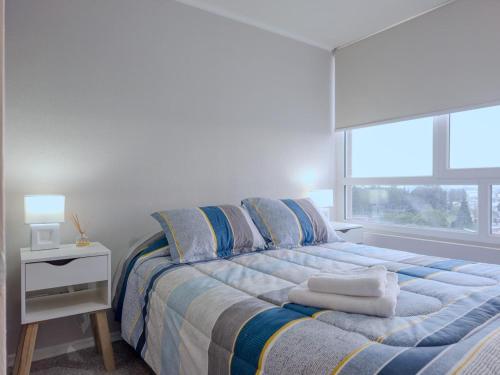 a bedroom with a bed with pillows and a window at Apart Total Aldunate Temuco Centro 2 in Temuco