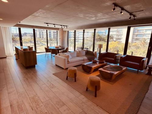 a living room with a couch and tables and windows at Surfside - 3 Suítes - 4 Bathroom in Punta del Este