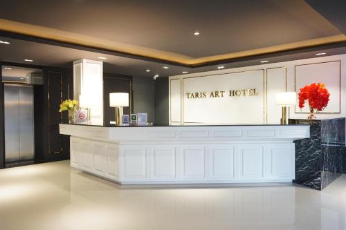 a hotel lobby with a reception counter with flowers at Taris Art Hotel Phrae in Phrae