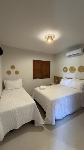 a bedroom with two beds with white sheets at Atins Brisa in Barreirinhas