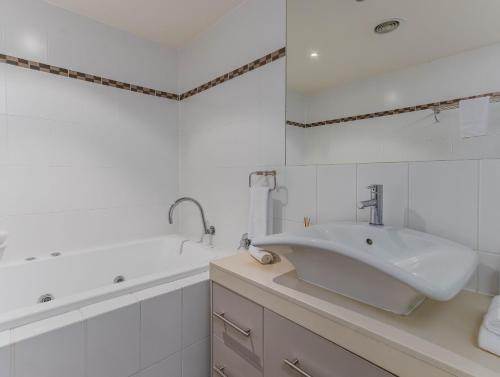 a white bathroom with a sink and a tub at Breakwater Views Apartment 2 Cabarita Beach in Cabarita Beach