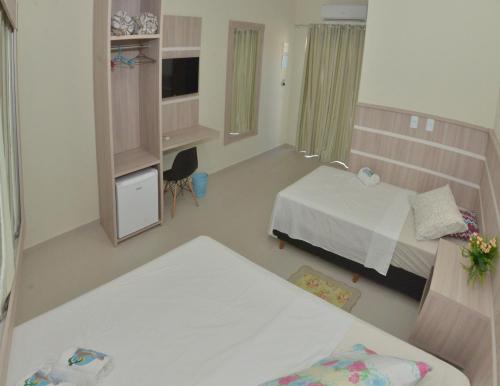 a room with two beds and a desk in it at Pousada Rota dos Mares in Penha