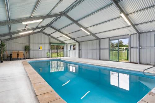 an indoor swimming pool with a metal building at Hunter Valley 2 x Homes Pets Heated Pool in Whittingham