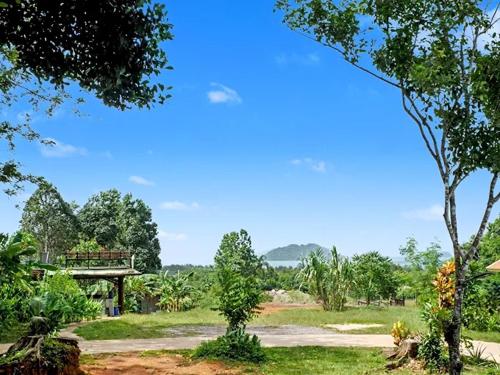 a park with a bench and a bridge and trees at Para Hill Homestay in Ban Muang Mai