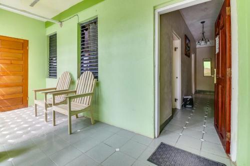 a room with two chairs and a table and a door at Suite Junior at Midas Belize in San Ignacio