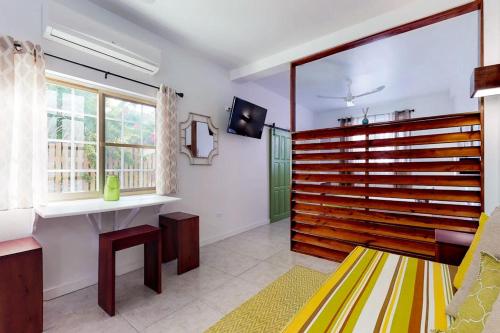 a living room with a bench and a tv at Rainforest Suite at Casa DV Suites -Gold Standard Certified in Caye Caulker
