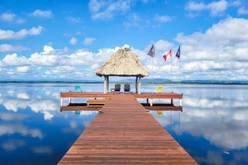 a dock with a straw umbrella and chairs on the water at Poseidon House in Riversdale