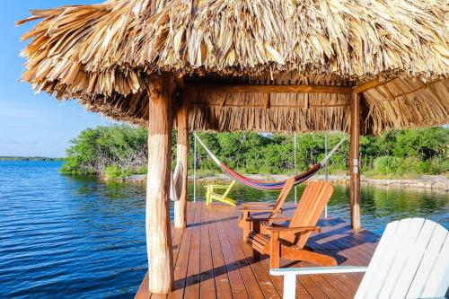a hut with two chairs and a hammock and water at Poseidon House in Riversdale