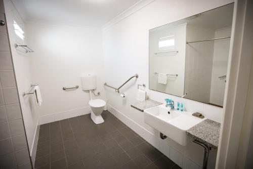 a bathroom with a sink and a toilet and a mirror at Albany Central Apartments in Albany