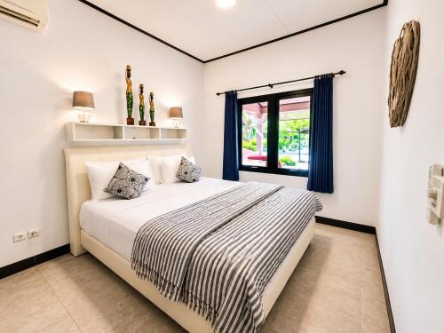 a white bedroom with a large bed and a window at Bugbug Beach Resort in Gili Biaha