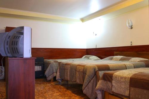 a hotel room with two beds and a flat screen tv at Residencial Victoria Said in Linares