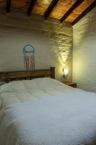 a bedroom with a white bed and a wooden ceiling at Potrerillos Nuestras Raíces in Potrerillos