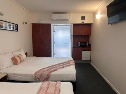a hotel room with two beds and a kitchen at Ayr Traveller's Motel in Ayr