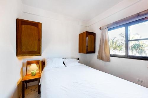 a bedroom with a white bed and a window at Affordable Suite with WiFi Partial AC Shared Rooftop Deck Pool and Grill in Caye Caulker