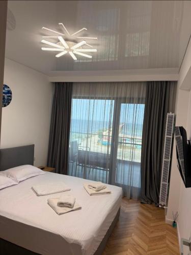 a bedroom with a bed and a large window at Ștefan Seafront Residence in Năvodari