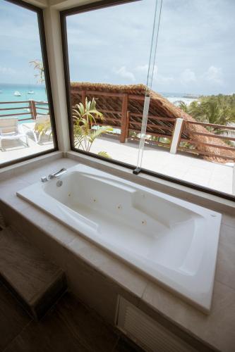 a white bath tub in a room with a window at Cuxos Hotel Beachfront in Isla Mujeres