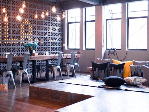 a dining room with a table and chairs with pillows at Silom Space Hostel in Bangkok