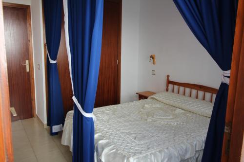 1 dormitorio con 1 cama con cortinas azules en Global Immo 1011 Meda Chica, en Roses