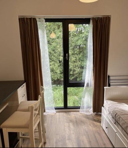 a bedroom with a large window with a bed and a desk at Riverside Apartment Tartu in Tartu