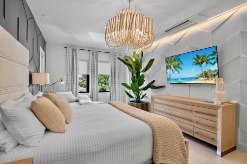 a white bedroom with a bed and a chandelier at Knot A Basic Beach House in Bailey Hall