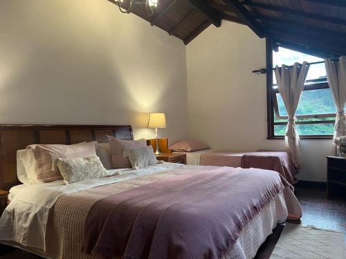 a bedroom with two beds and a large window at Casa Holanda - luxury guesthouse in Teresópolis