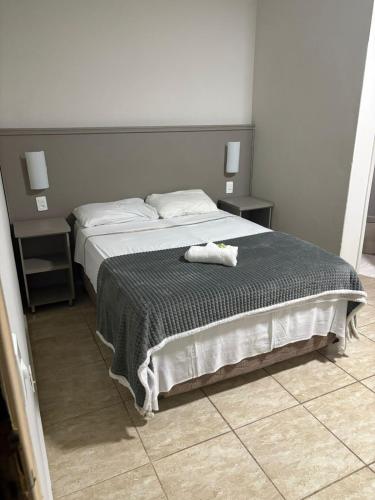 a bedroom with a large bed with two tables at Quefren Residence Hotel in Uberaba
