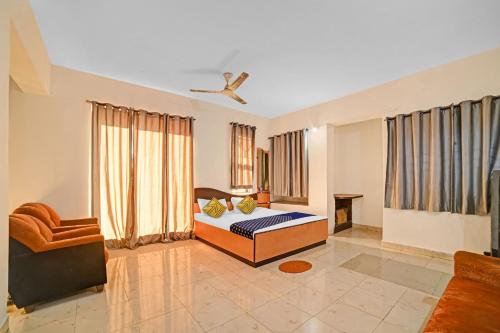 a bedroom with a bed and a chair in a room at Hotel O SS in Chandrapur