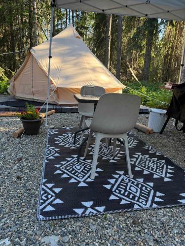 a table and a chair on a rug with a tent at Willowbank Bell Tent in Golden