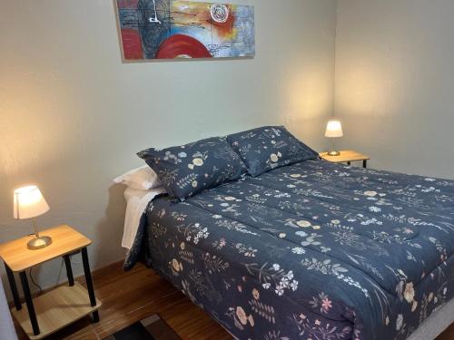 a bedroom with a bed and two tables with lamps at Apart Hotel Colon in La Serena