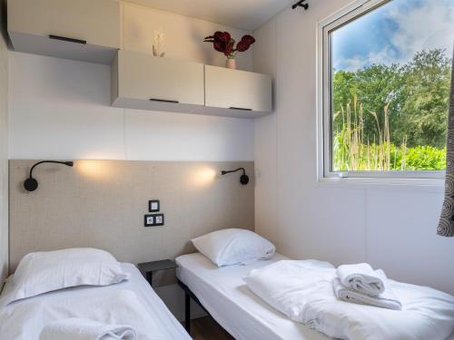 two beds in a room with a window at Comfortable caravan in a green setting in Vierhuizen