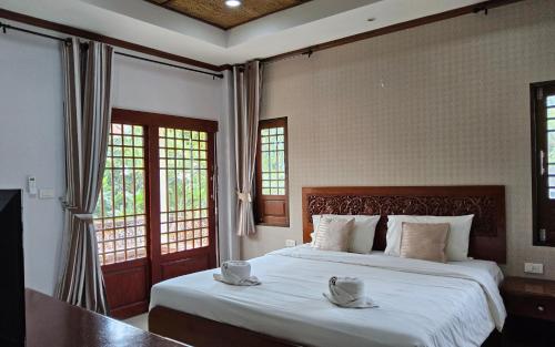 a bedroom with a bed with white sheets and windows at Fueangfu Pool Villa Chaweng in Chaweng