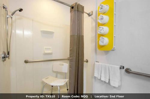 a bathroom with a shower with a chair and towels at El Paso Inn in Ysleta