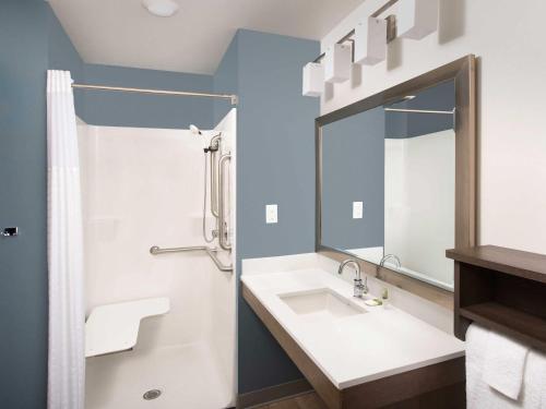 a bathroom with a sink and a mirror at WoodSpring Suites in Glendale