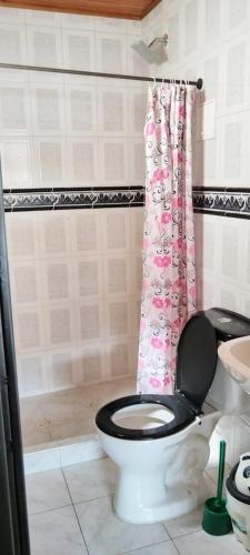 a bathroom with a toilet with a pink shower curtain at Casa Vacacional Algarrobos in Girardot
