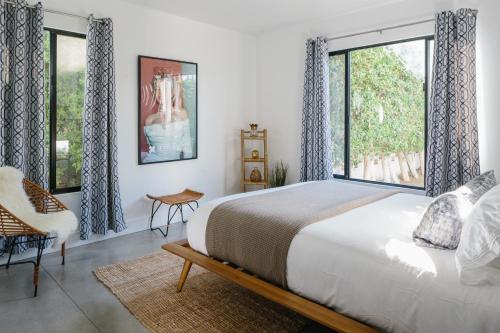 a bedroom with a bed and a large window at Hotel El Cid by AvantStay in Palm Springs