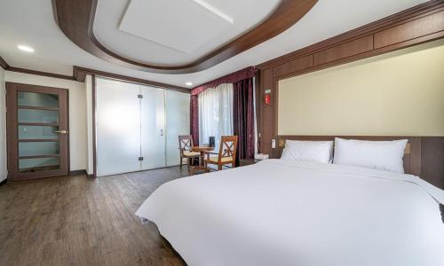 a bedroom with a large white bed and a table at Mobydick Hotel in Yangyang