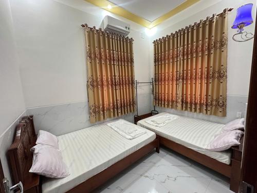 two beds in a small room with curtains at Biệt Thự Villa Thảo Vy in Ly Son