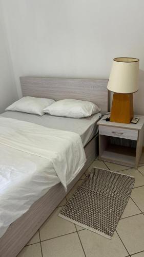 a bedroom with a bed and a nightstand with a lamp at RESIDENCE CYBERVILLAGE THREE ROOMS Apartment in Ebene