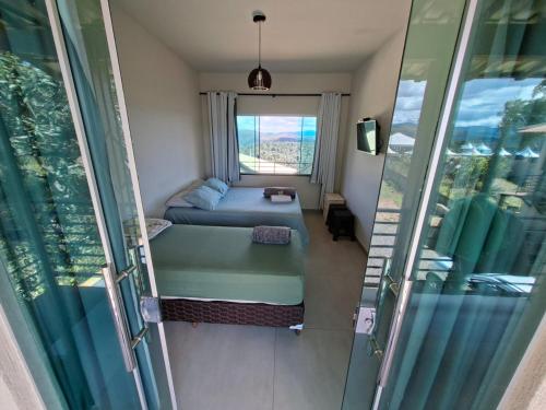 a small room with a bed and a window at Pousada altavista acuruí in Itabirito
