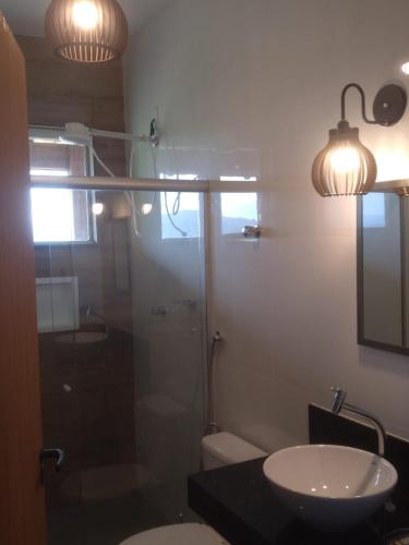 a bathroom with a glass shower and a sink at Pousada altavista acuruí in Itabirito