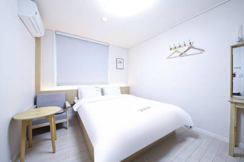 a white bedroom with a bed and a chair at 통영호텔조선 in T'ongyŏng