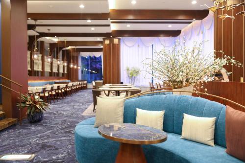 a lobby with a blue couch and tables at Hotel Springs Makuhari Premier in Chiba