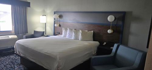 a hotel room with a large bed and a chair at AmericInn by Wyndham Lincoln North in Lincoln
